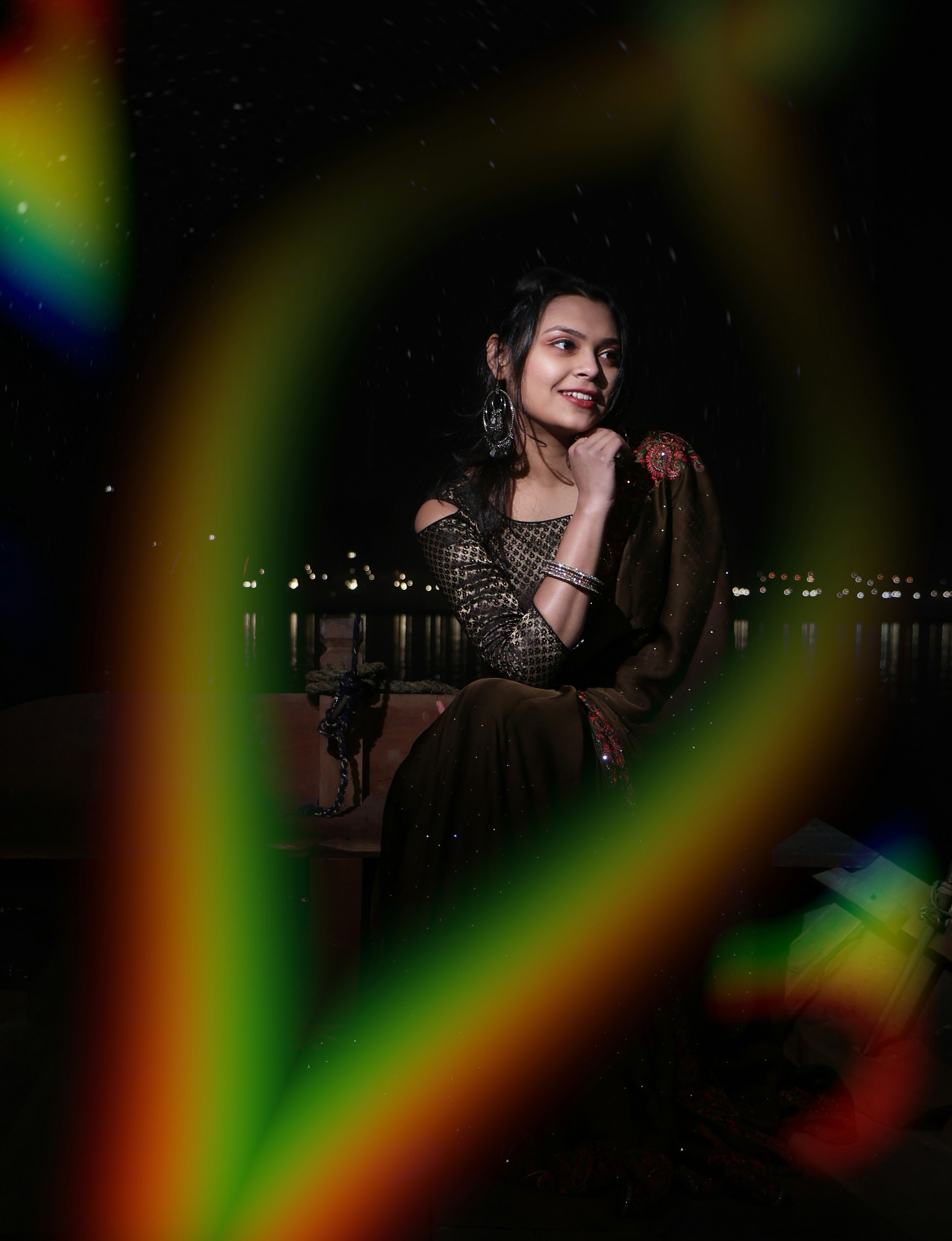 A woman sitting on a bench with a rainbow in the background
