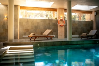 A large swimming pool with a lounge chair next to it