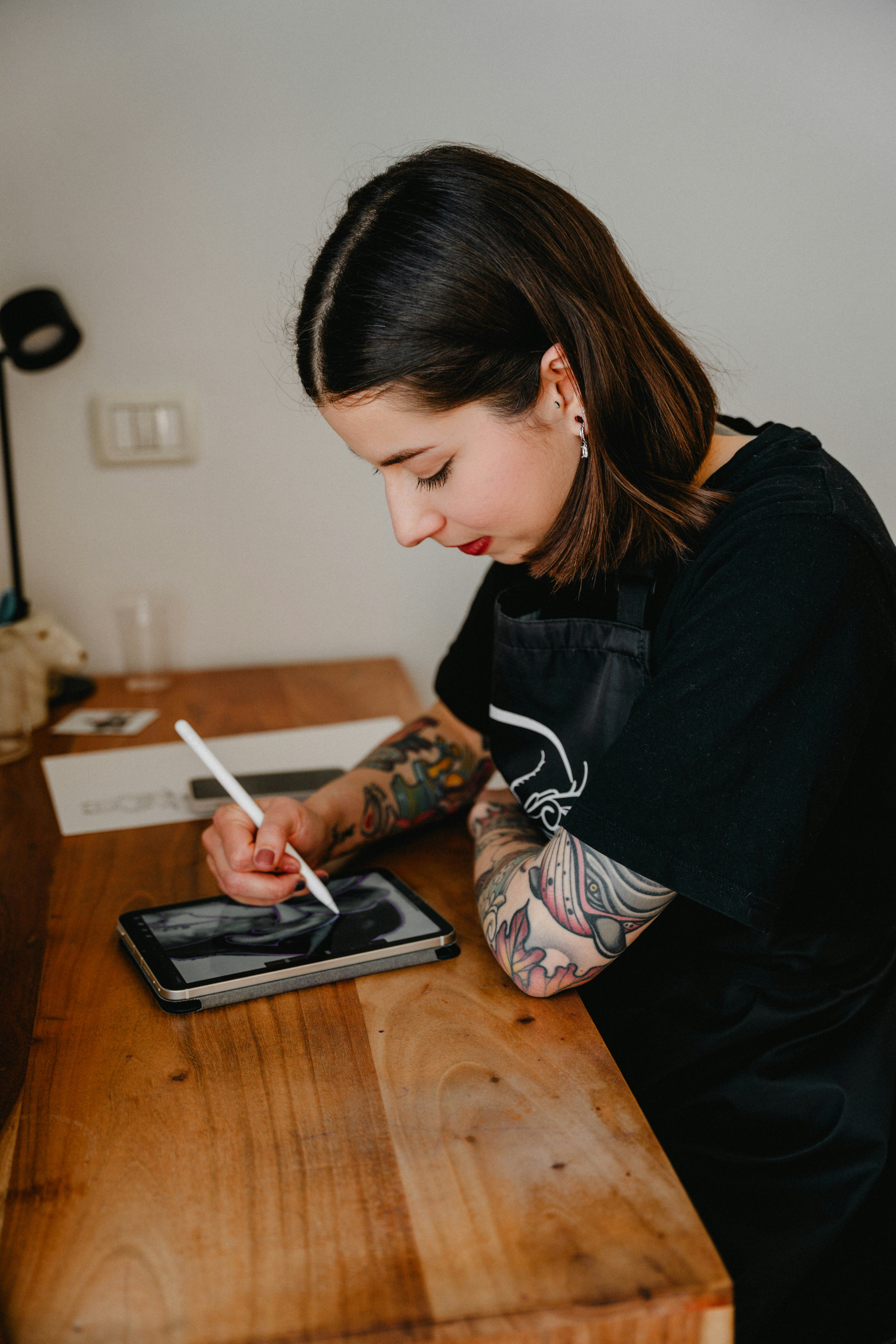 A woman sitting at a table writing on a tablet