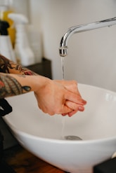 A person washing their hands under a faucet