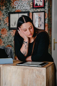 A woman sitting at a desk with her hand on her face