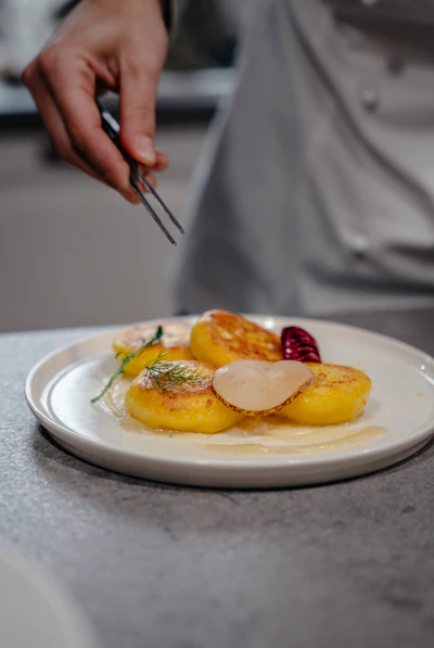 A chef delicately garnishing a minimalist tasting-menu plate with tweezers
