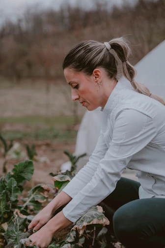 A woman kneeling down in a field next to a tent