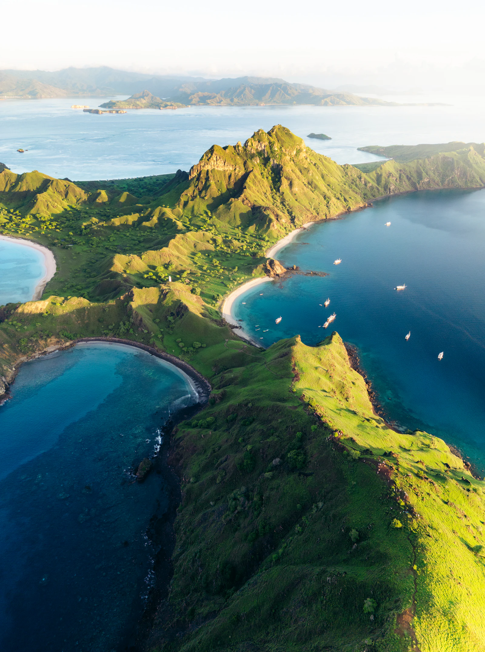 Phinisi boat sailing between islands at golden hour