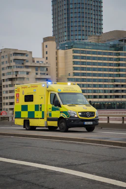 A yellow ambulance driving down a street next to tall buildings
