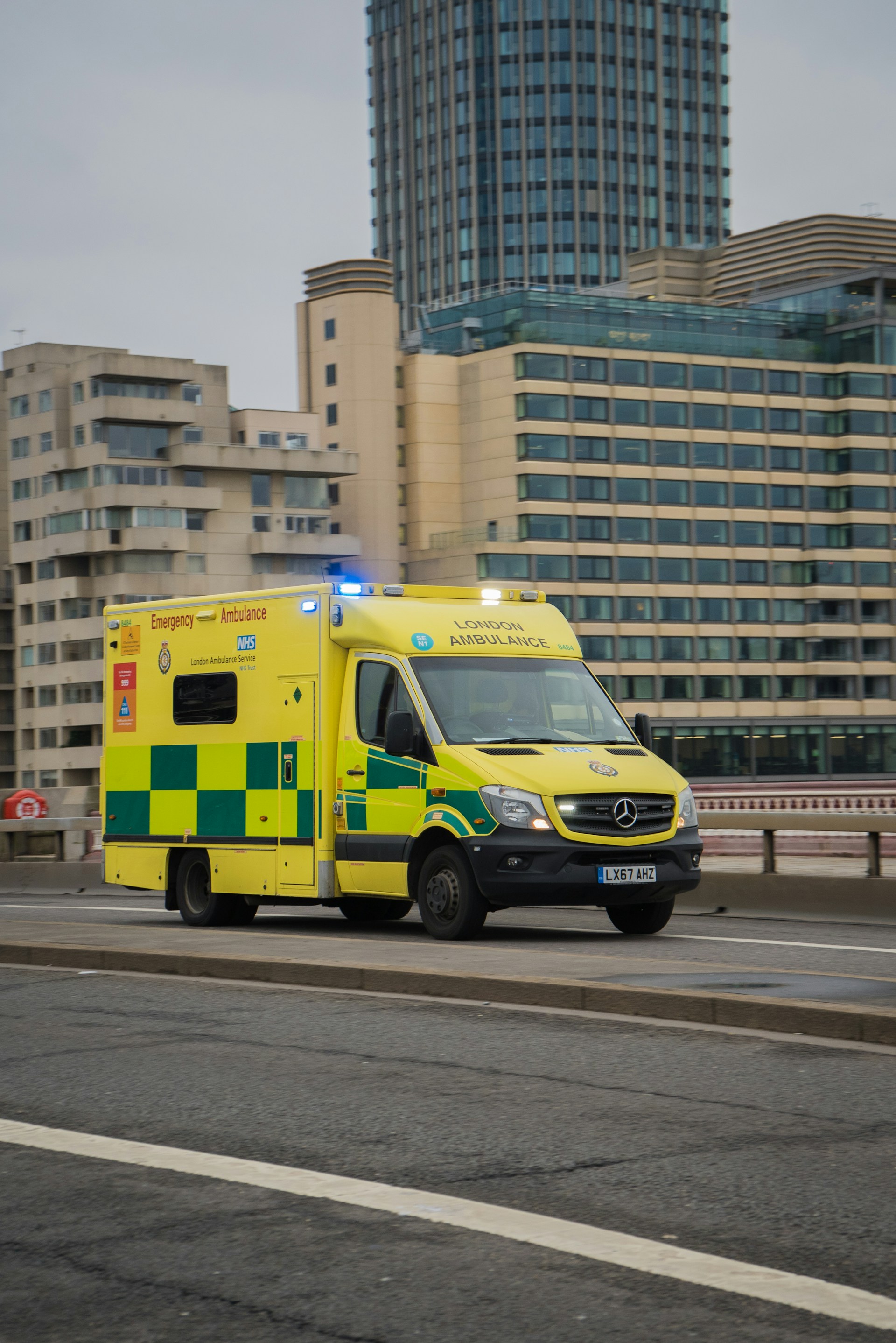 A yellow ambulance driving down a street next to tall buildings