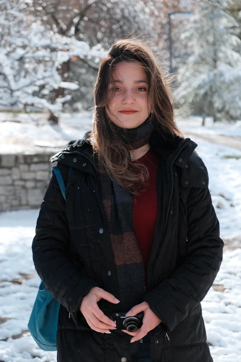 A woman standing in the snow holding a camera