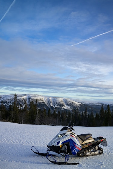 A snowmobile is parked on a snowy hill