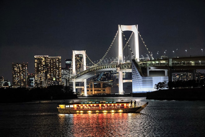 A large boat floating on top of a river next to a bridge