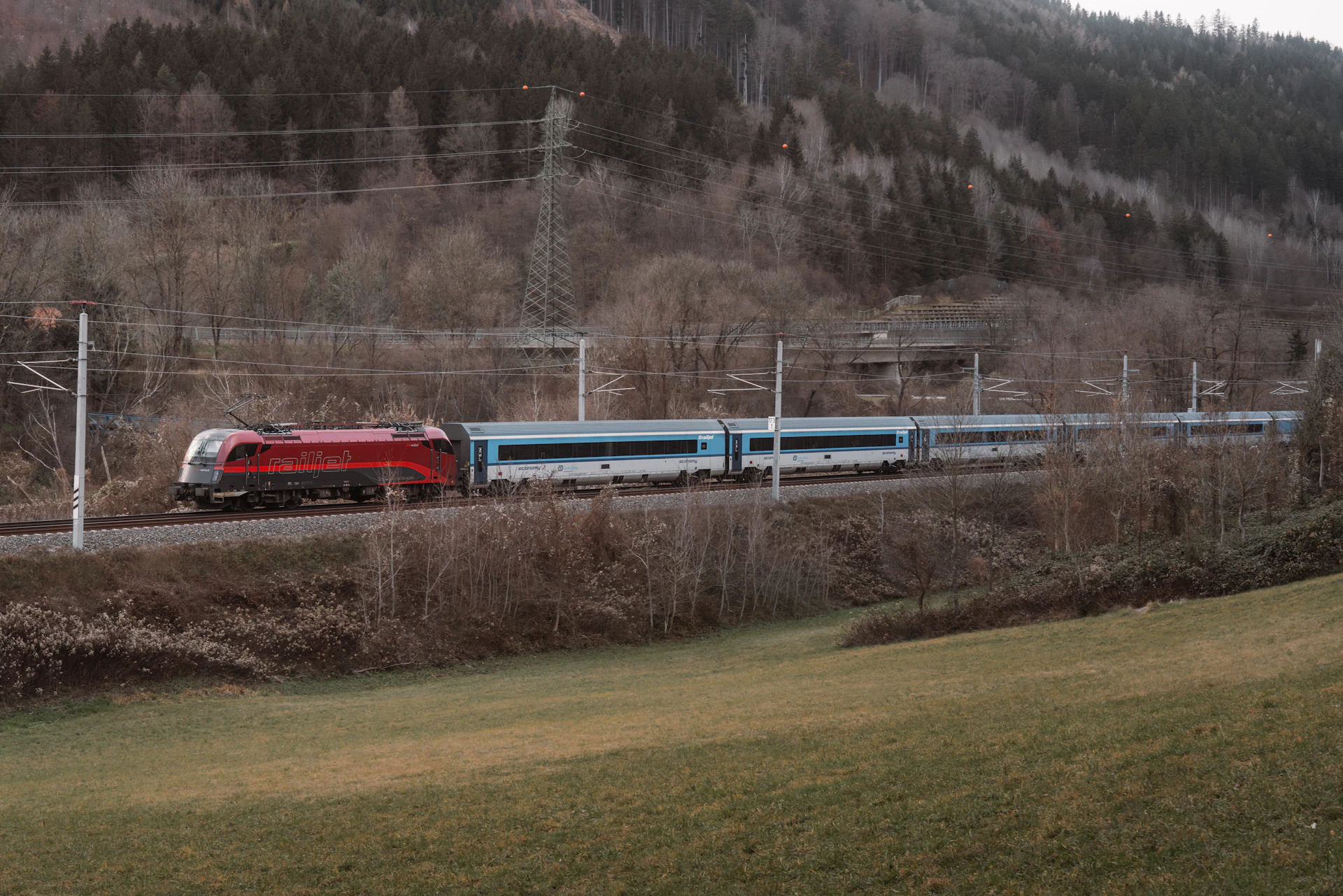 A train traveling down tracks next to a lush green hillside