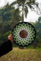 A person holding a green and white plate with a flower design on it