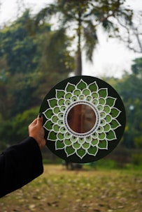 A person holding a green and white plate with a flower design on it