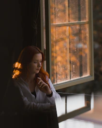 A woman sitting in a chair looking out a window