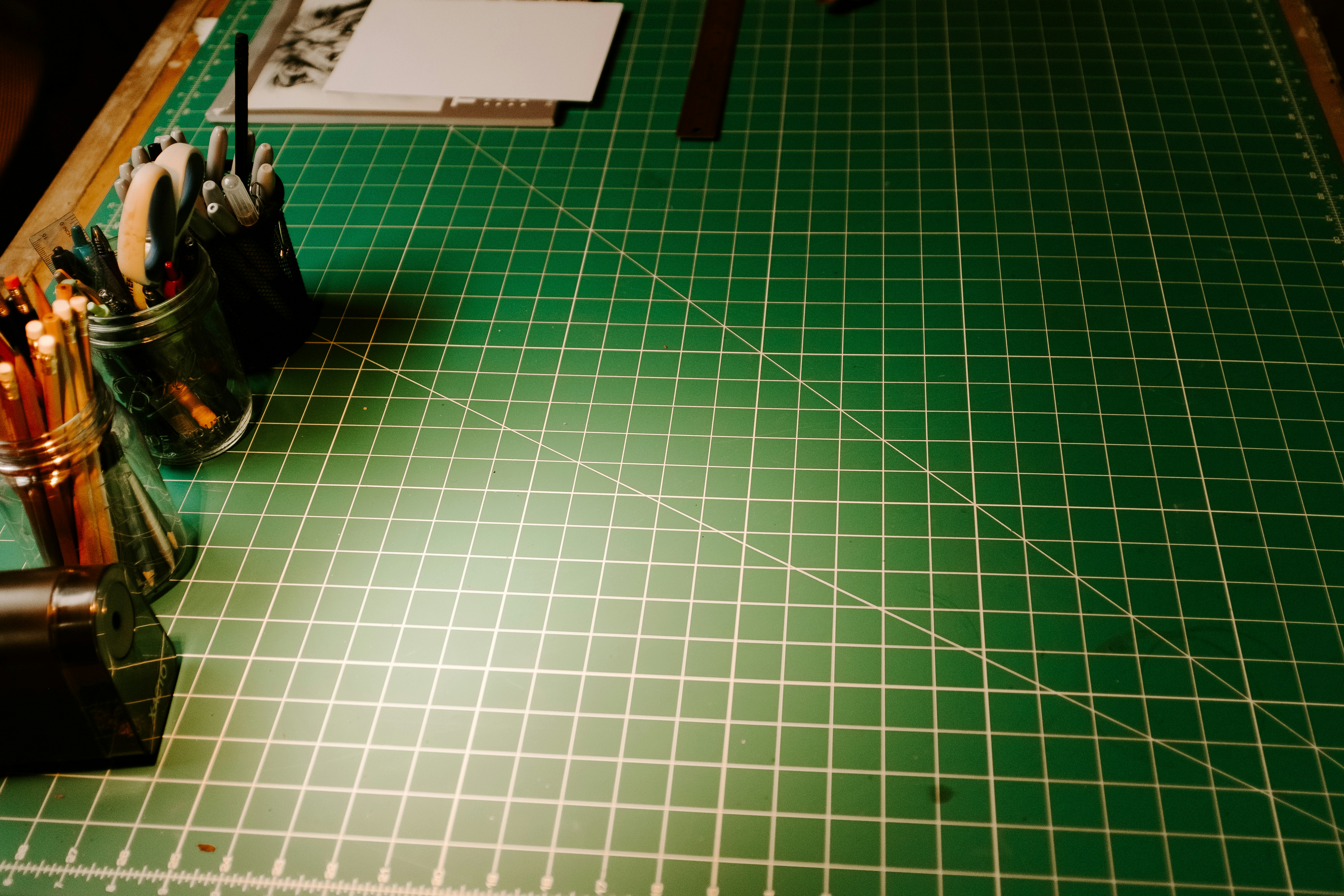 A green cutting mat with a knife and a pair of scissors