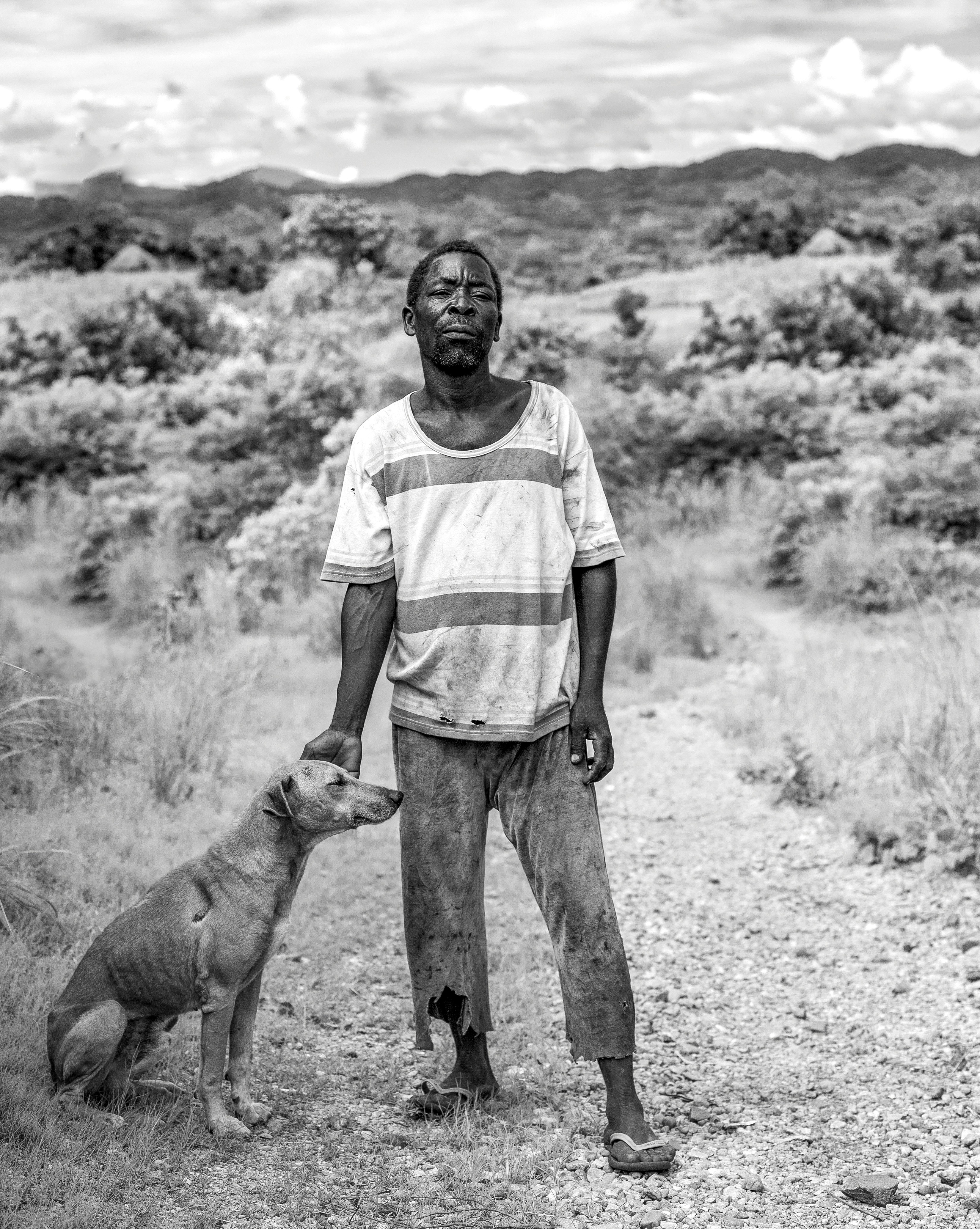 A man standing next to a dog on a dirt road