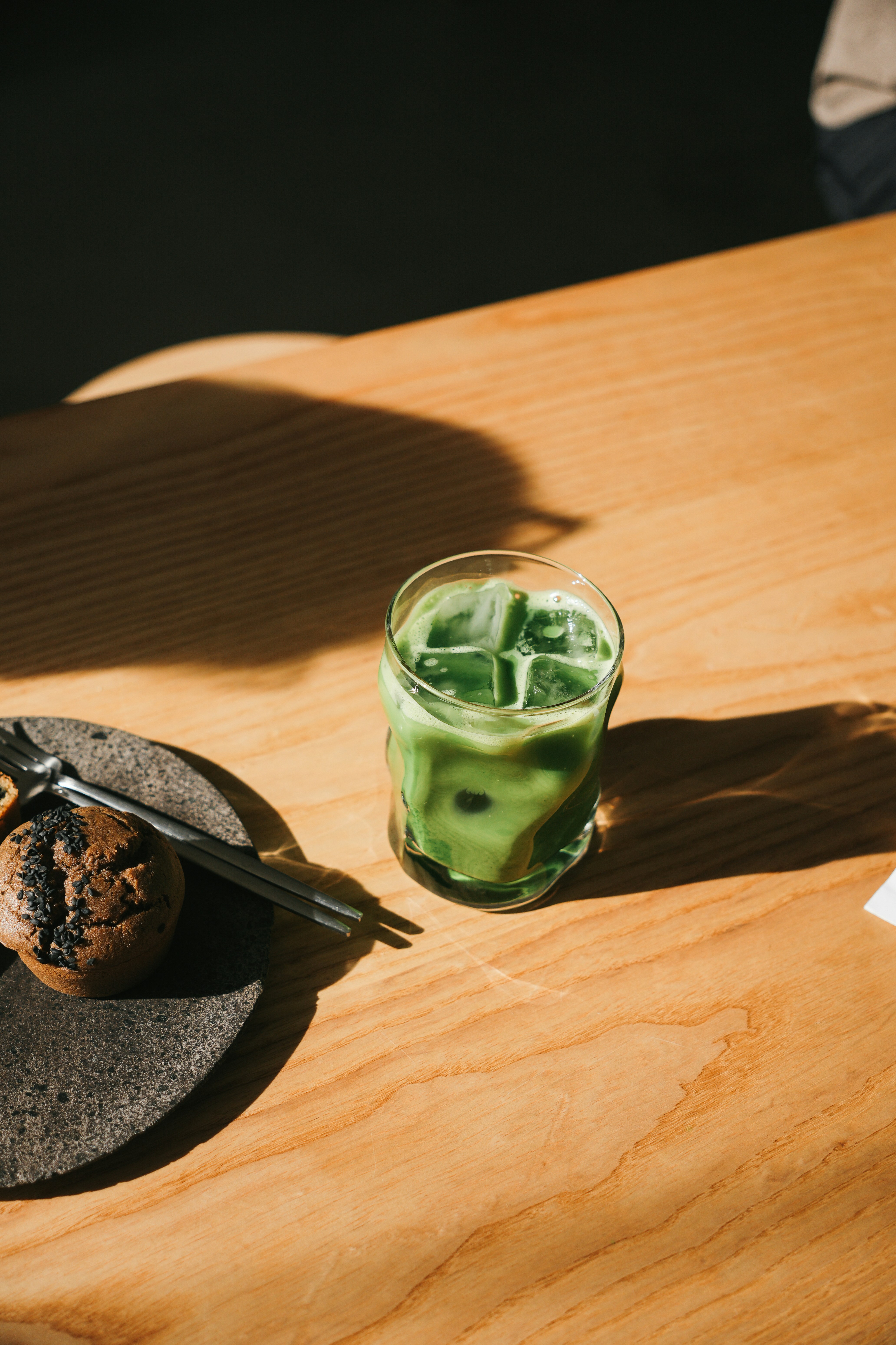Ein Holztisch mit einem Teller mit Essen und einem Glas grüner Flüssigkeit