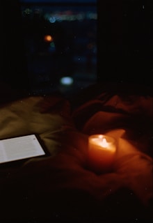 A lit candle and a book on a bed