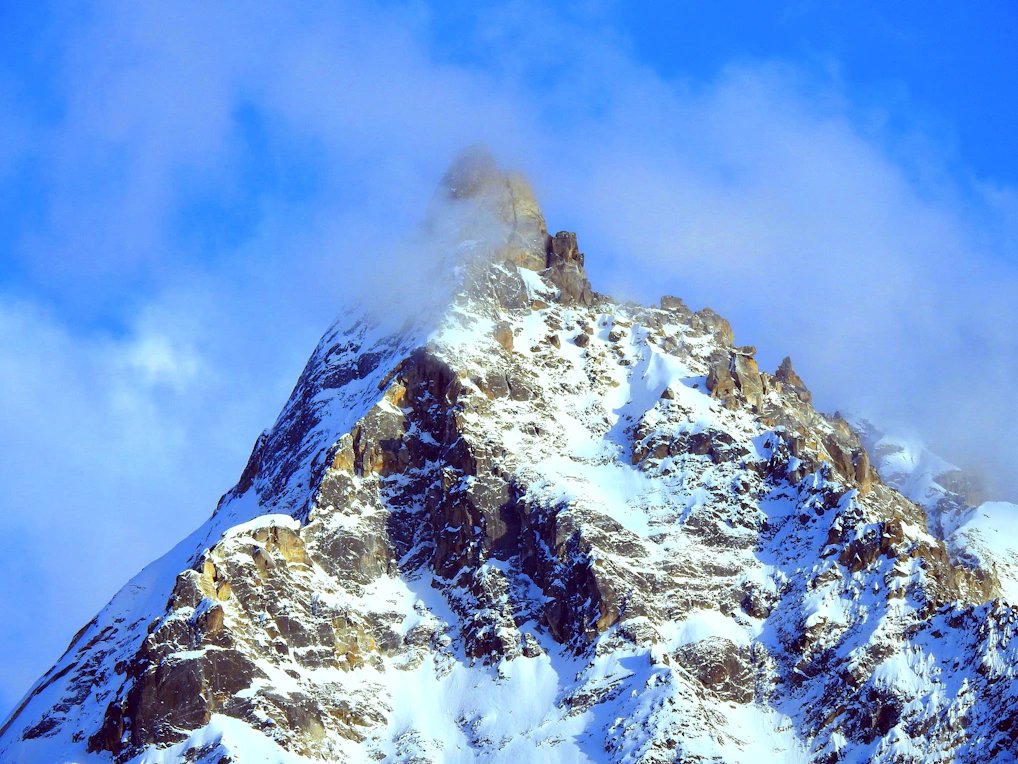 A large mountain covered in snow under a blue sky