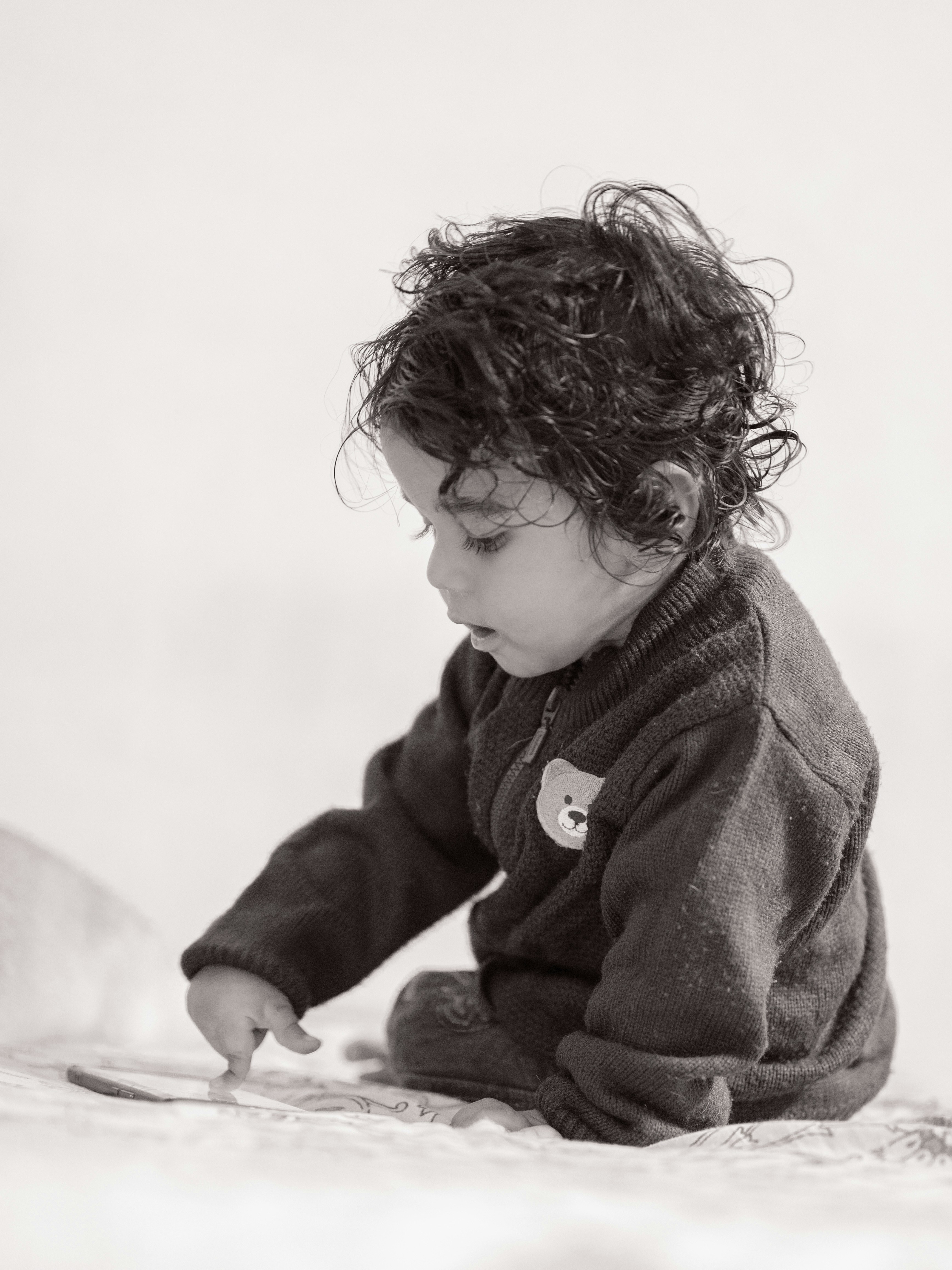 A baby sitting on a bed playing with a toy