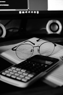 A computer desk with a keyboard, mouse and glasses on it
