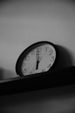 A black and white photo of a clock on a shelf
