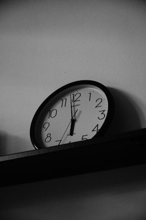 A black and white photo of a clock on a shelf