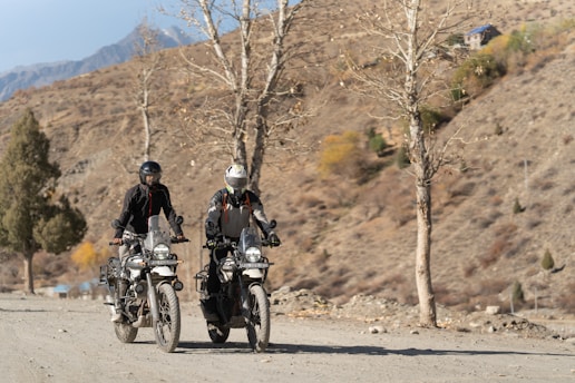 Two people riding motorcycles down a dirt road