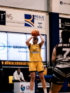 A woman in a yellow uniform is playing basketball