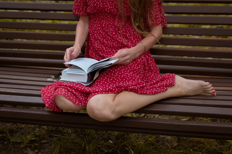 A woman sitting on a bench reading a book