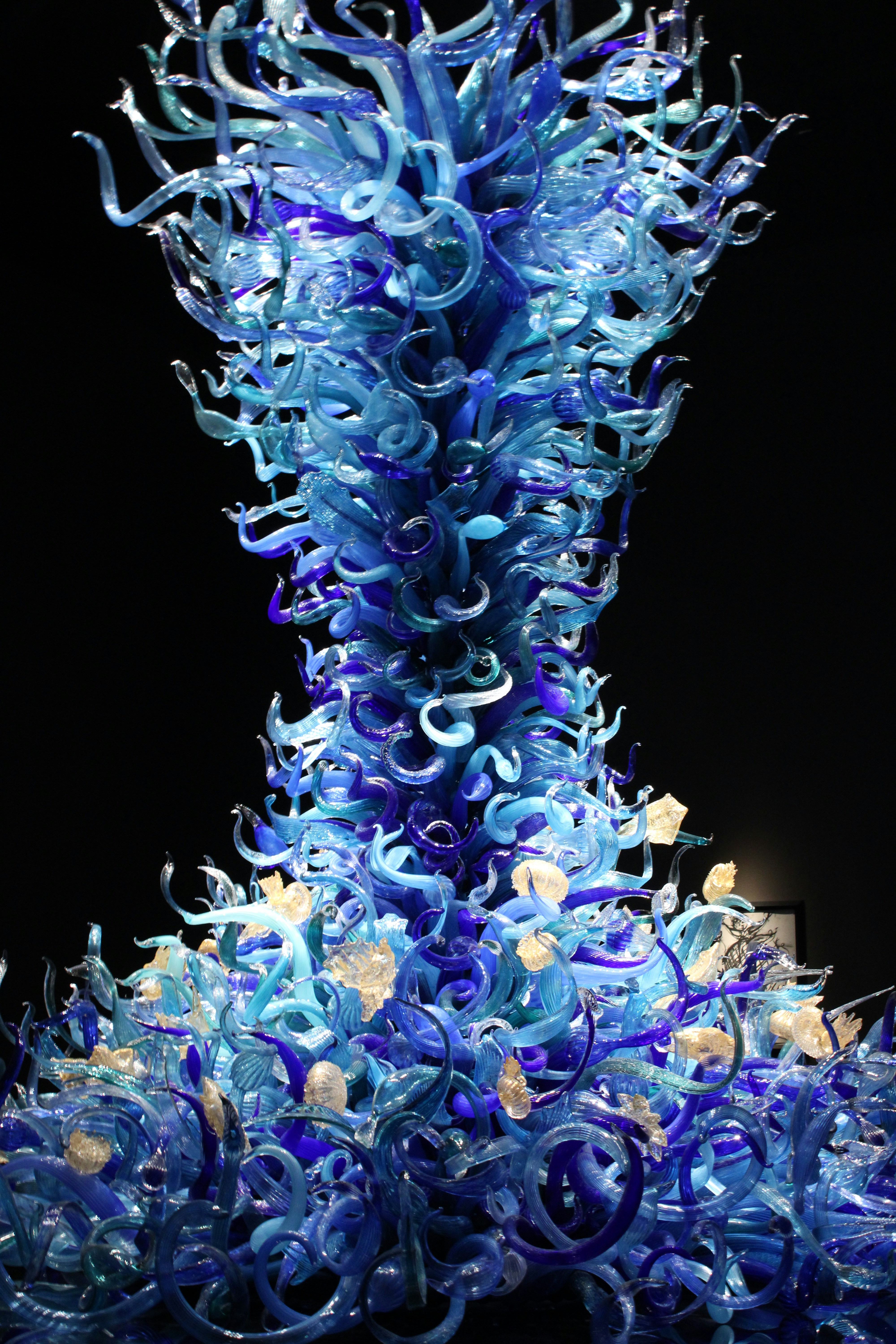 A very tall blue glass sculpture in the dark