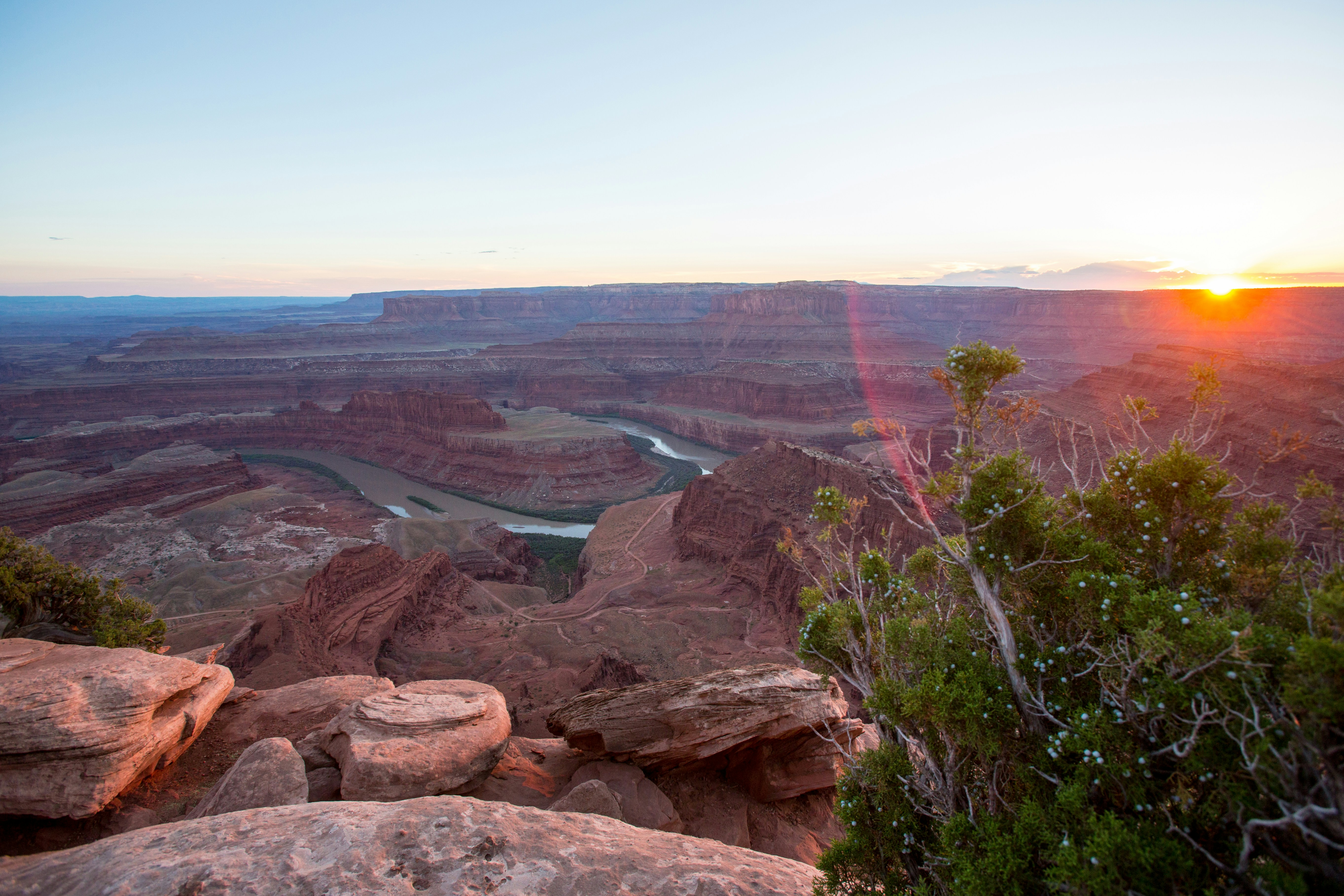 The sun is setting over a canyon with a river running through it