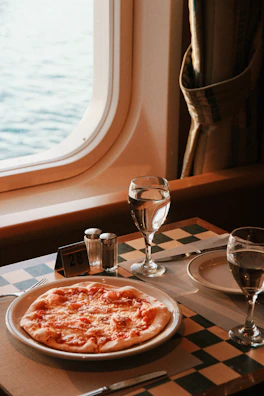 A table with a plate of pizza and a glass of water