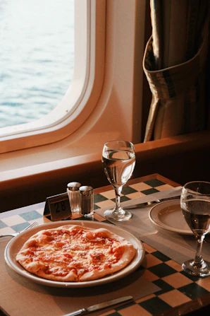 A table with a plate of pizza and a glass of water