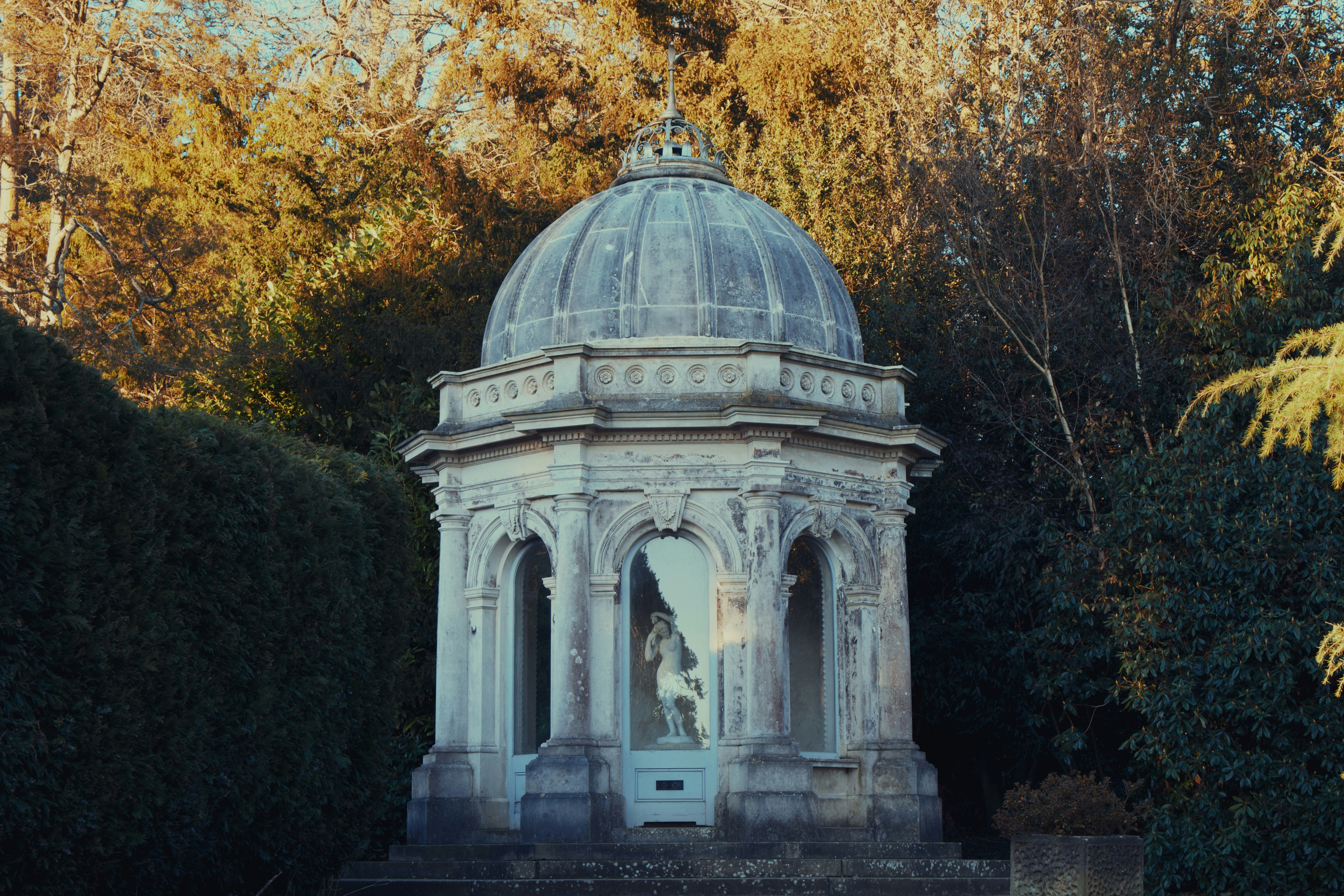 A gazebo in the middle of a park surrounded by trees