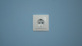 A white electrical outlet on a blue wall