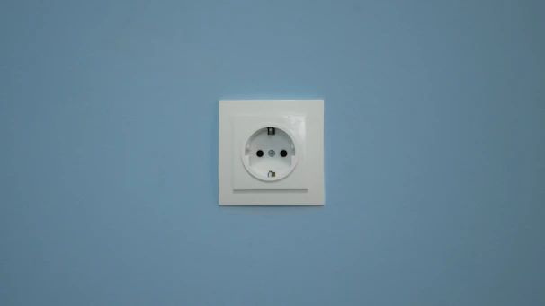A white electrical outlet on a blue wall