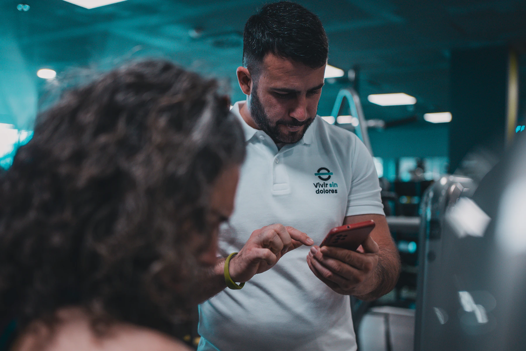 Coach et sportive regardant ensemble les charges de la séance sur un téléphone