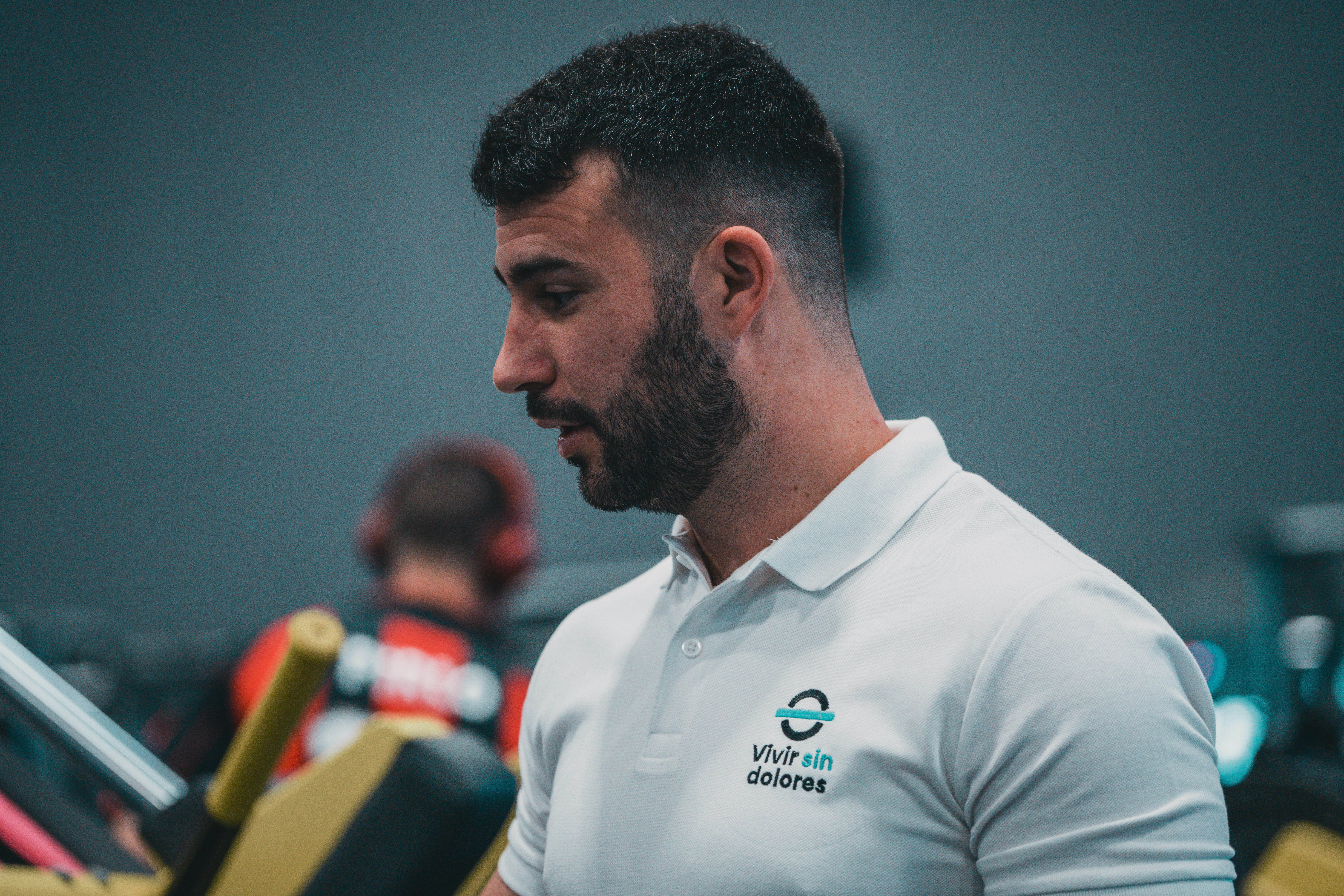 A man in a white shirt is looking at his cell phone