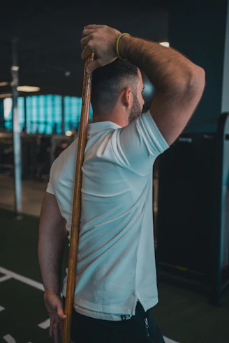 A man holding a baseball bat in a gym