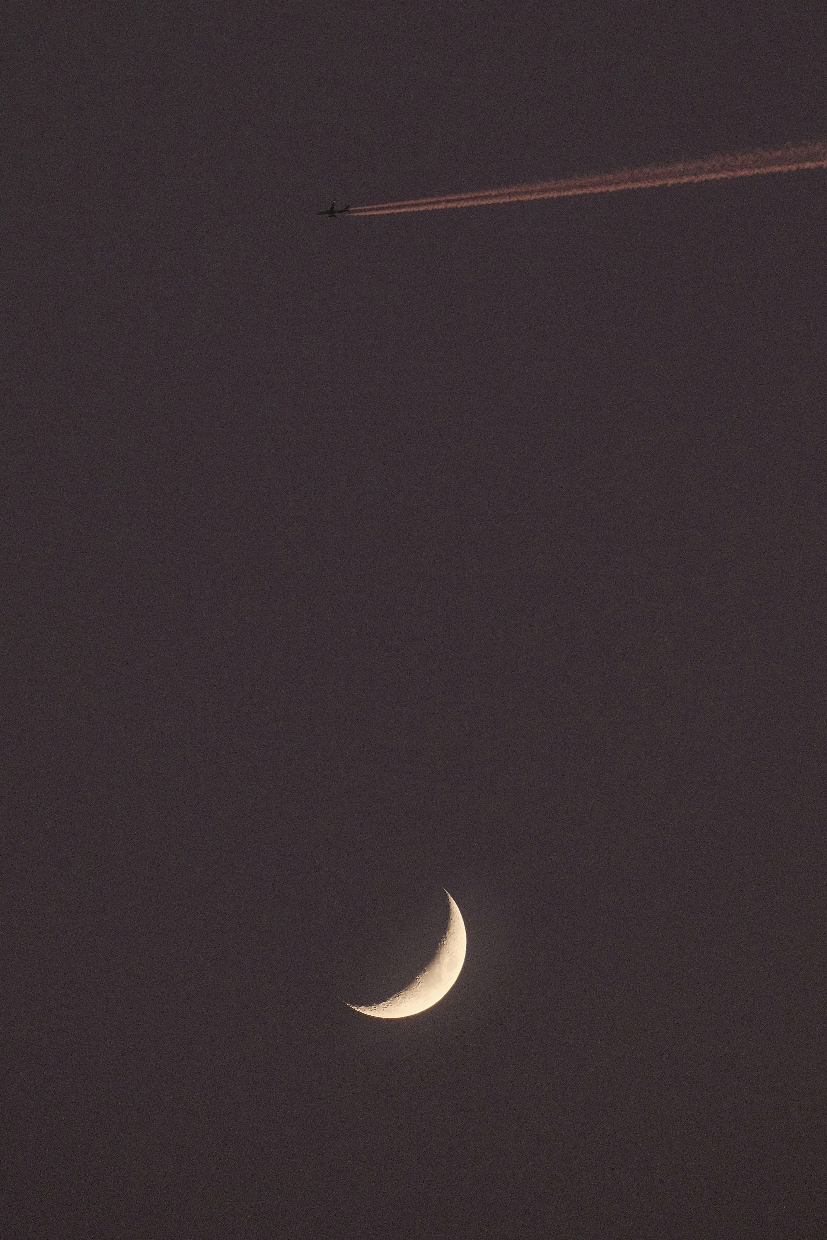 A plane flying in the sky with the moon in the background