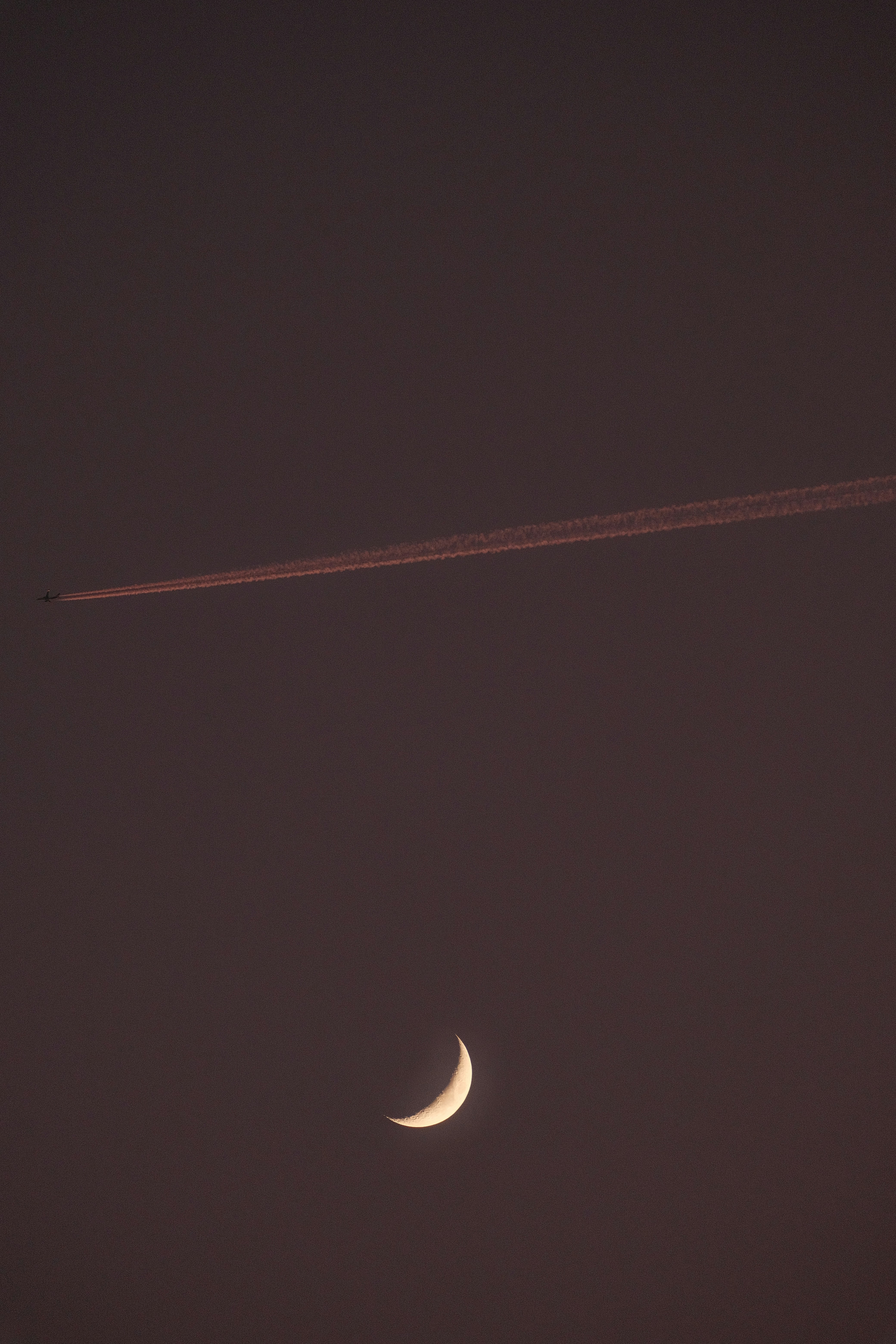 A plane flying in the sky with the moon in the background