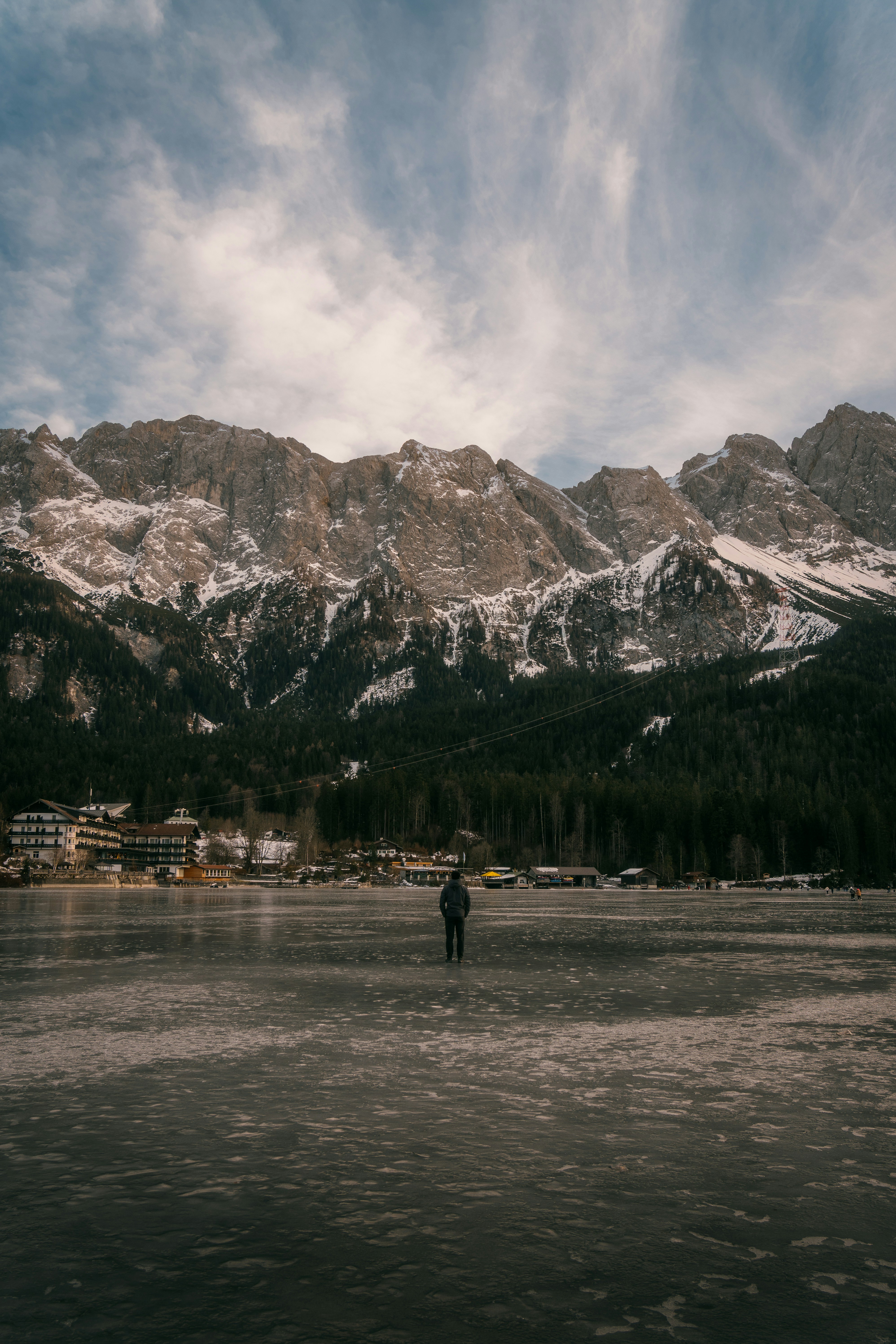 A man standing on a frozen lake with mountains in the background