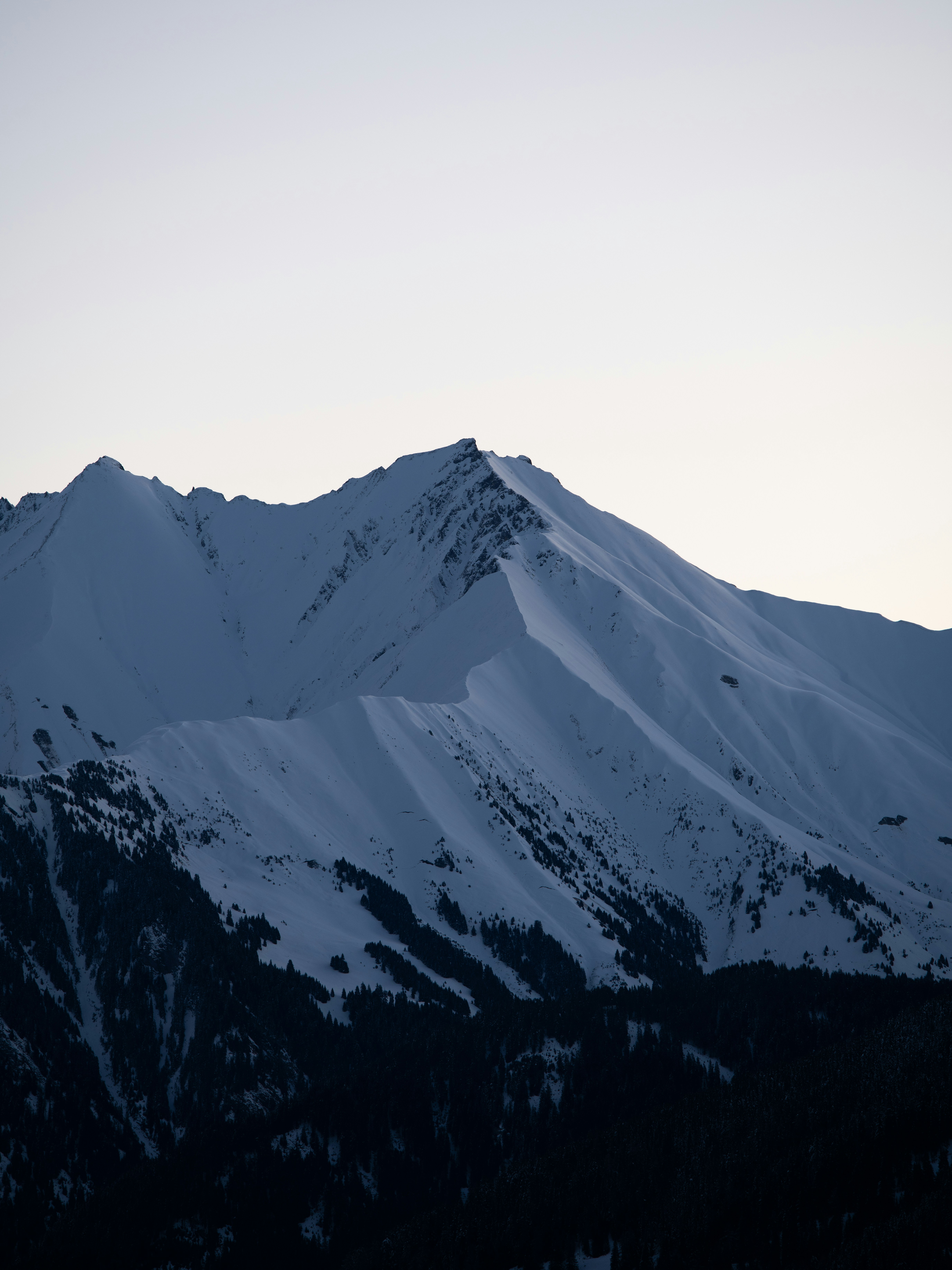 A large mountain covered in snow under a blue sky