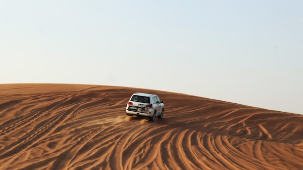 A white truck driving across a sandy field