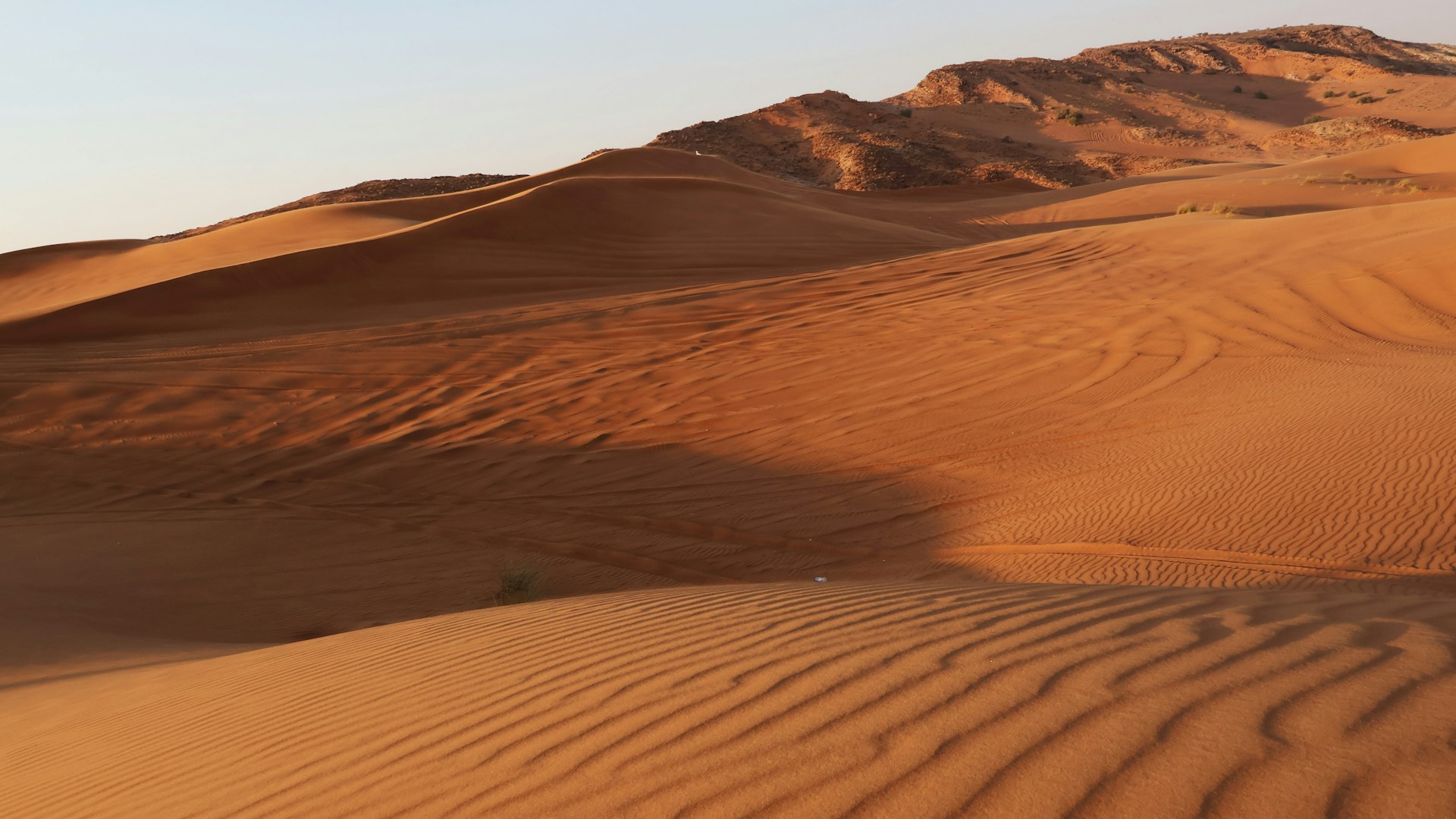 A desert landscape with sand dunes and mountains