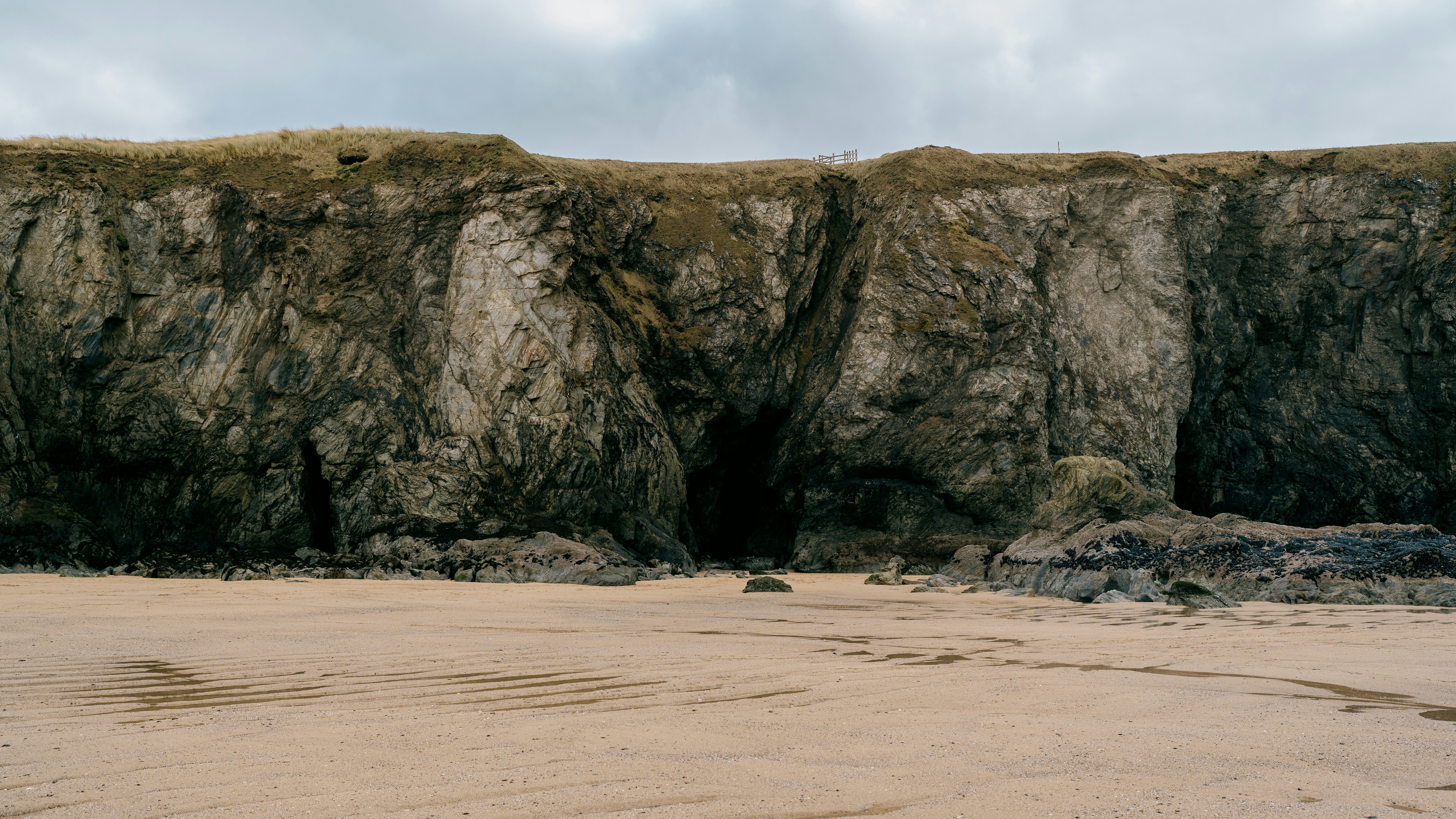 A sandy beach next to a large cliff