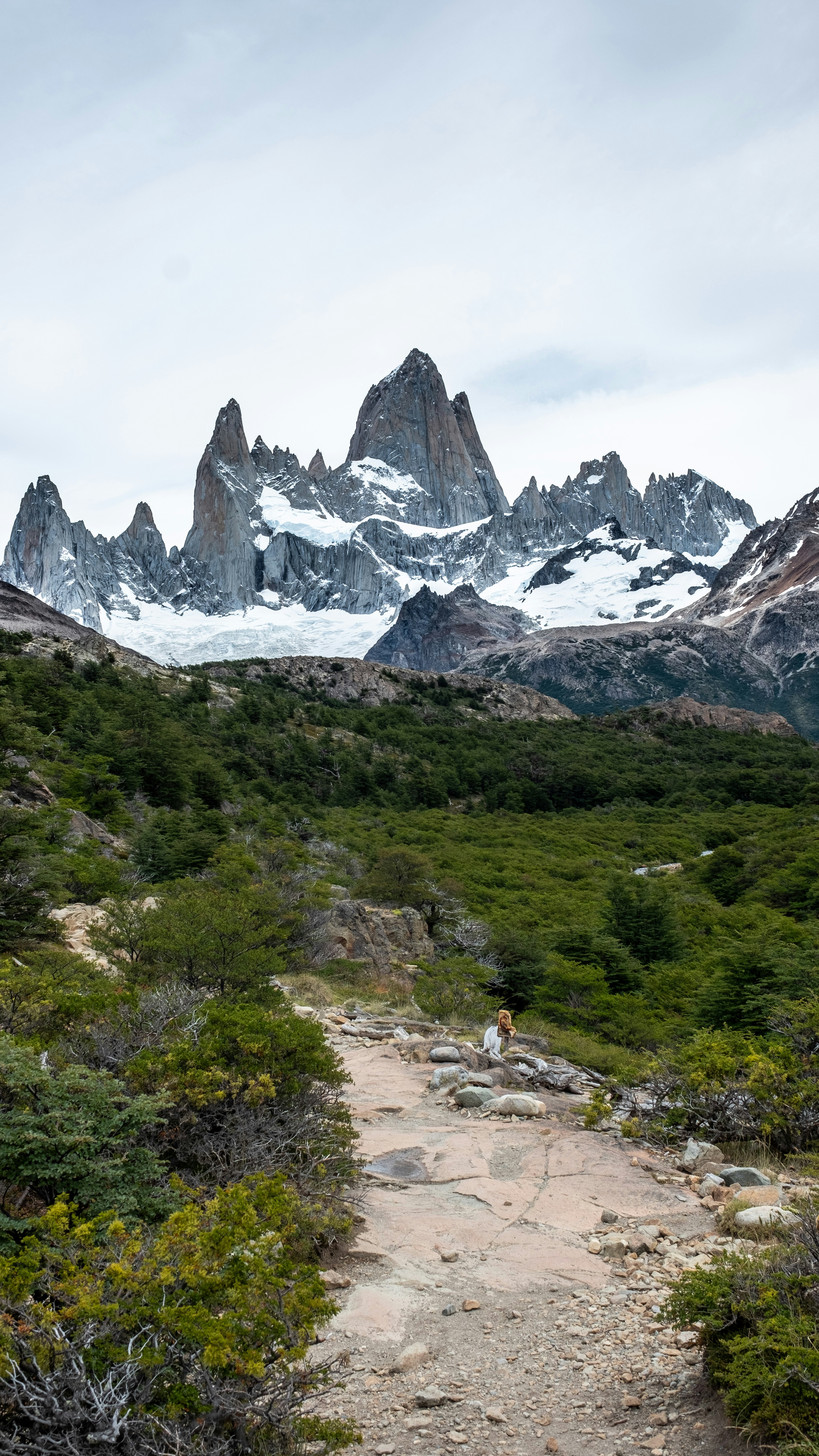 A trail in the mountains with snow on the top