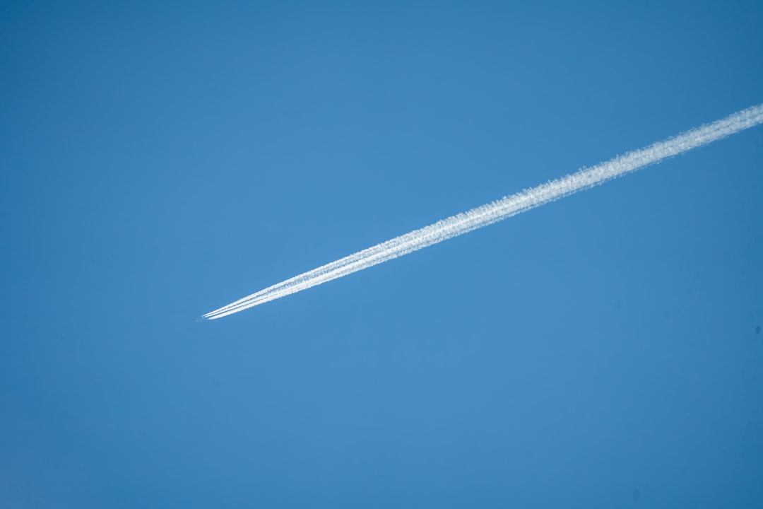 A jet flying through a blue sky with a contrail, Airplane crossing blue sky, leaving long contrails.