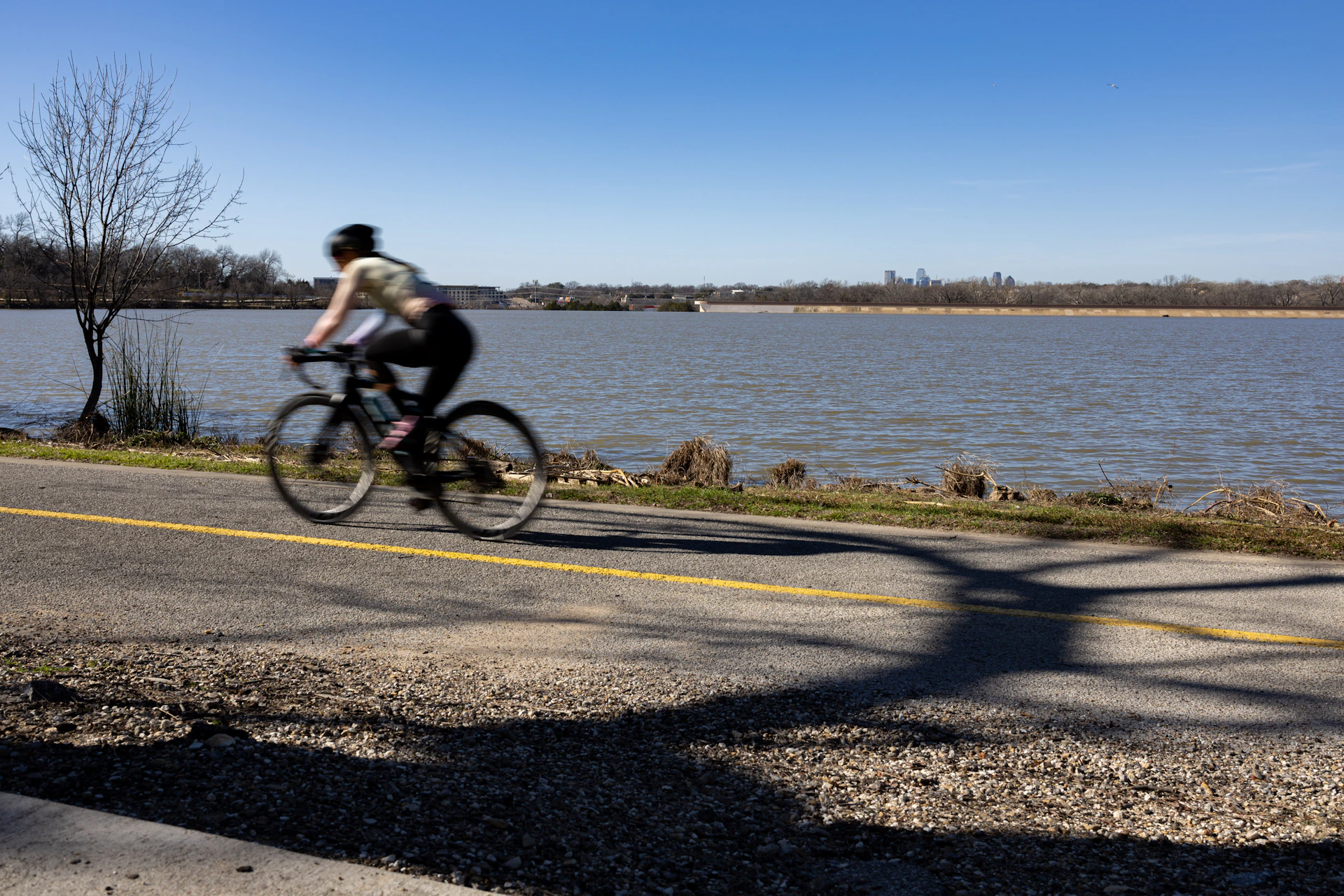 A man riding a bike down a street next to a lake