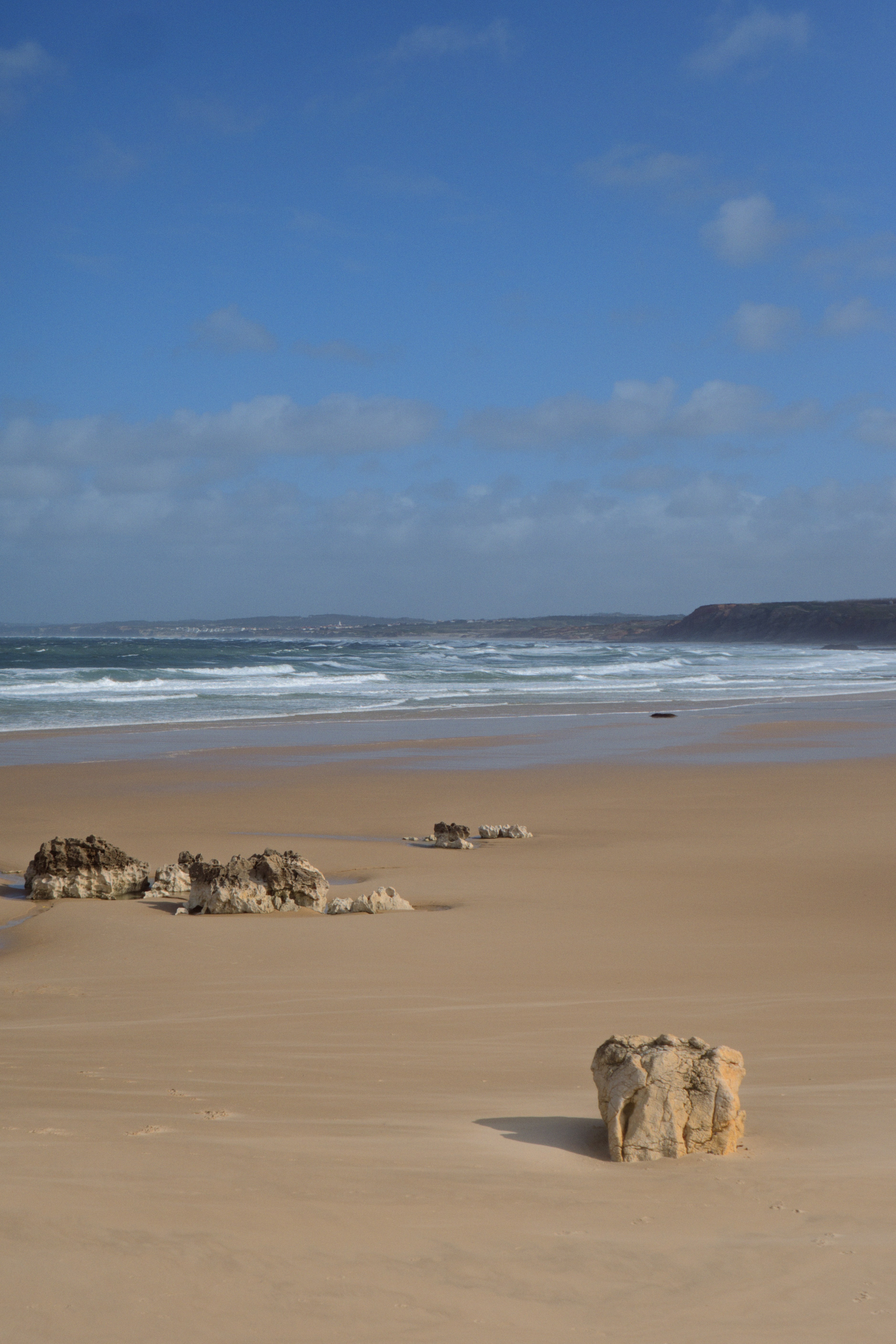 A sandy beach next to the ocean under a blue sky
